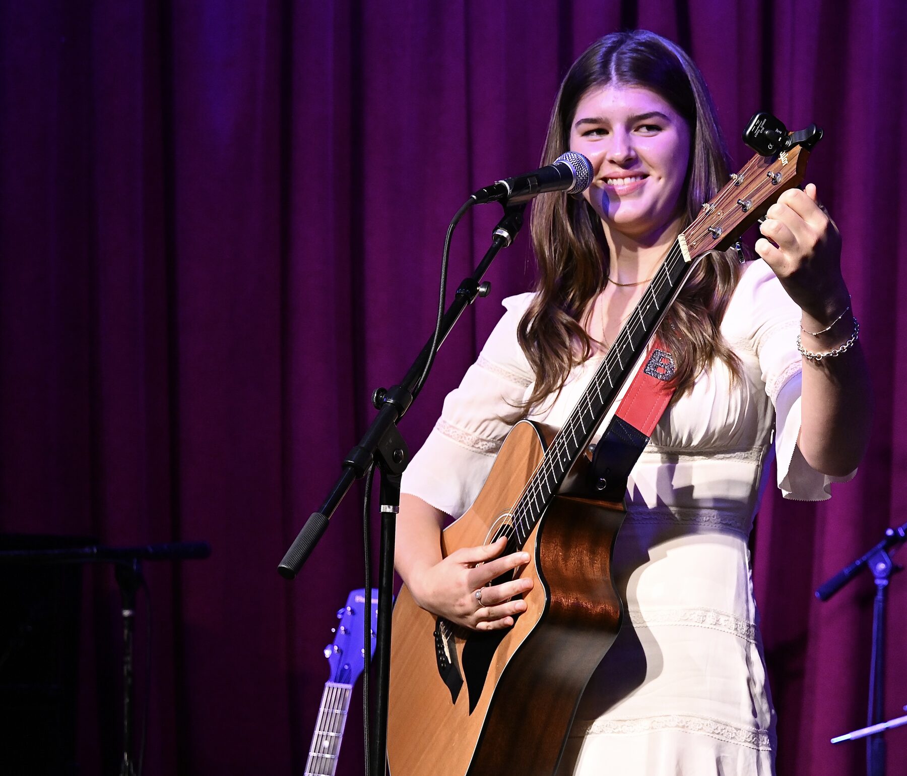 Carolina Chase performing live, on guitar smiling